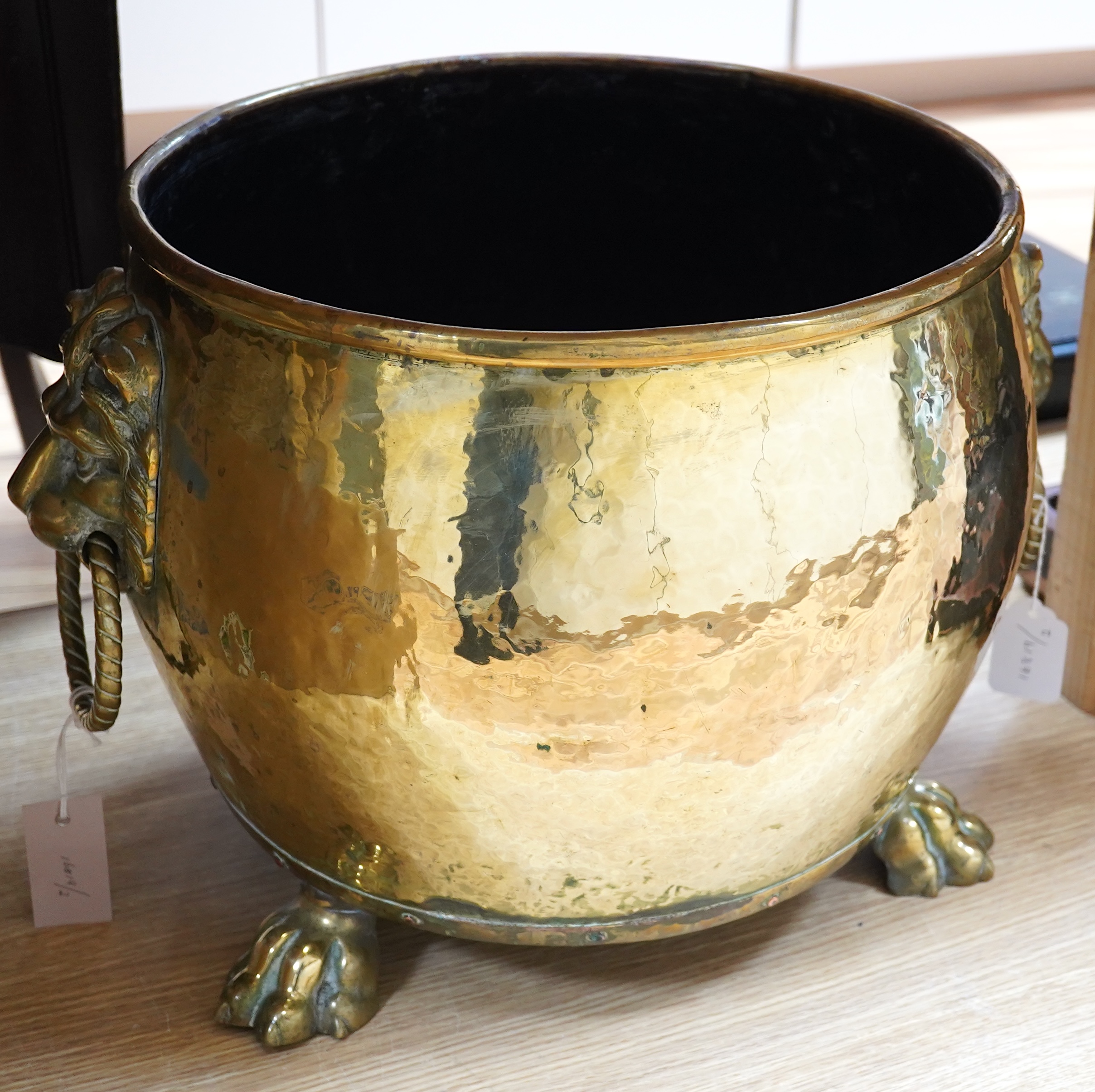 A large Victorian brass log bucket with lions head handles and paw feet, 50cm in diameter. Condition - fair to good